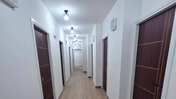A long, narrow hallway with wooden flooring and white walls, leading to multiple doors. - Hotel Backpack   BTS Punnawithi PKK2 (Bangkok)