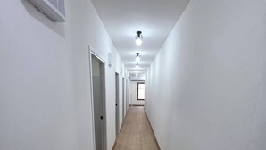 A narrow hallway with white walls and a wooden floor, leading to a door at the end. - Hotel Backpack   BTS Punnawithi PKK2 (Bangkok)