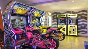 Arcade machines with racing motorcycles, a patterned wall, and a tiled floor.