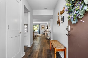 A hallway with a wooden bench, a door, and a wall-mounted light fixture. - Courtside 67 - Your Perfect Hilton Head Island Getaway (Hilton Head Island)
