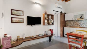 Una cocina compacta con horno integrado, cafetera y comedor con mesa y sillas de madera.