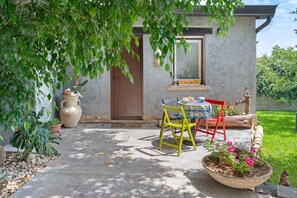 Eine Terrasse mit Tisch, Stühlen, einem Blumentopf und einer Tür.