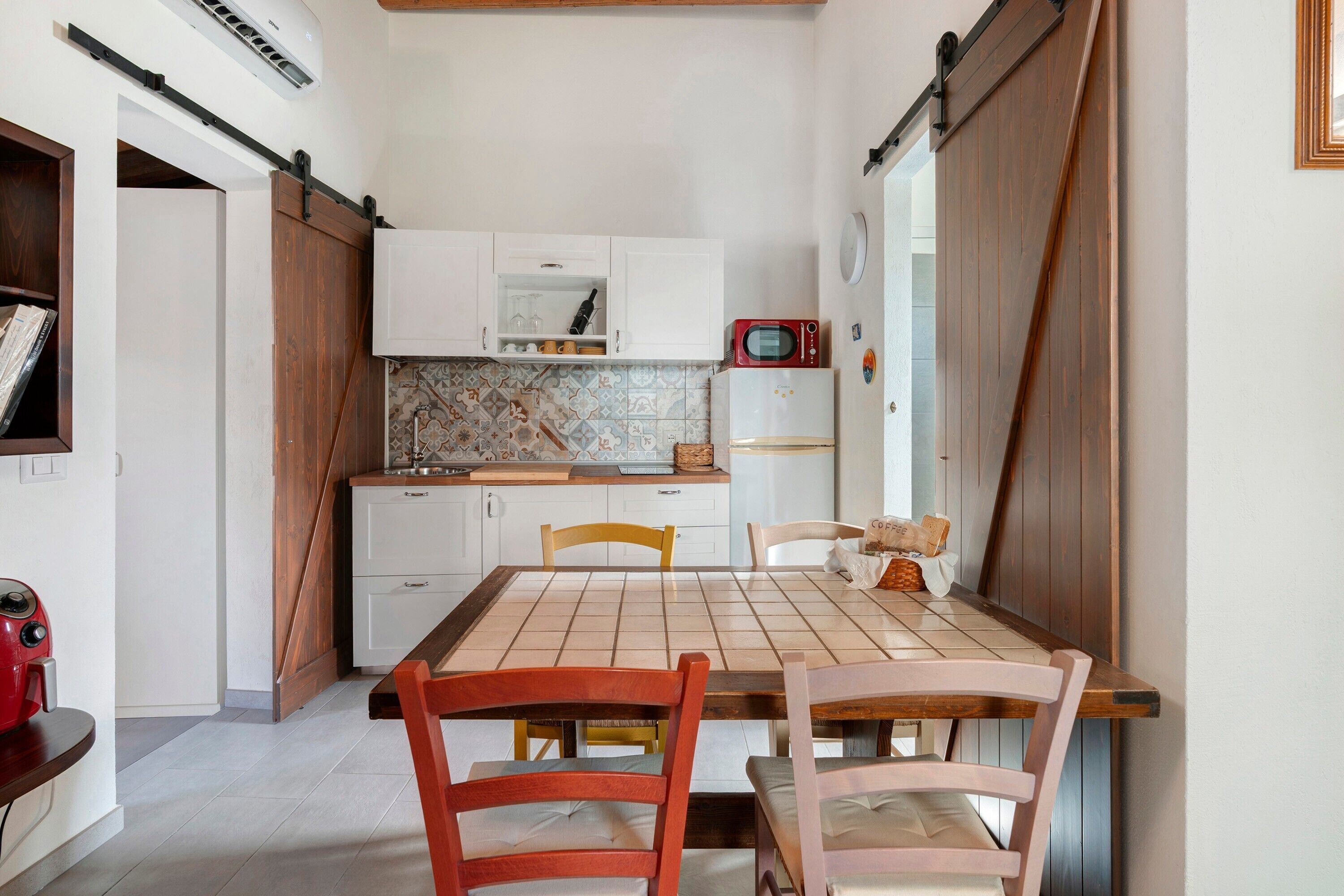 A compact kitchen with a dining table, chairs, and basic appliances.