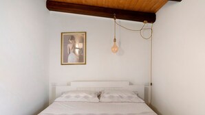 Een slaapkamer met een bed, een ingelijste foto en een hanglamp.