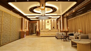 Een hotel lobby met een receptiebalie, een zithoek en een kroonluchter.
