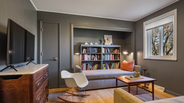 Ein modernes Wohnzimmer mit Bücherregal, Fernseher, Sofa und Couchtisch.
