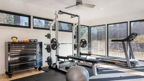 Ein Heimfitnessraum mit einer Gewichtbank, Kettlebells, einem Squat-Gestell und einem Laufband.