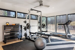 A home gym with a weight bench, kettlebells, a squat rack, and a treadmill. - Aalto Modern - Spacious, 5-bed MCM - A Luxury KY Derby Vacation! (Louisville)