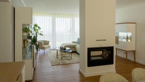 A modern living room with a fireplace, a sofa, a coffee table, and a glass cabinet with plants. - Casa das Hortênsias (Nossa Senhora do Pilar Terceira)