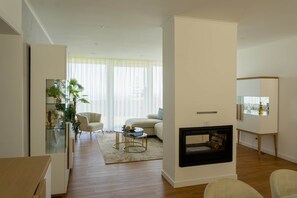 En moderne stue med pejs, sofa, sofabord og et vitrineskab med planter.