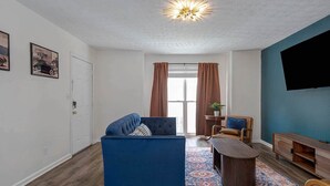 Ett vardagsrum med en blå soffa, ett soffbord och en tv som är monterad på en blå vägg.