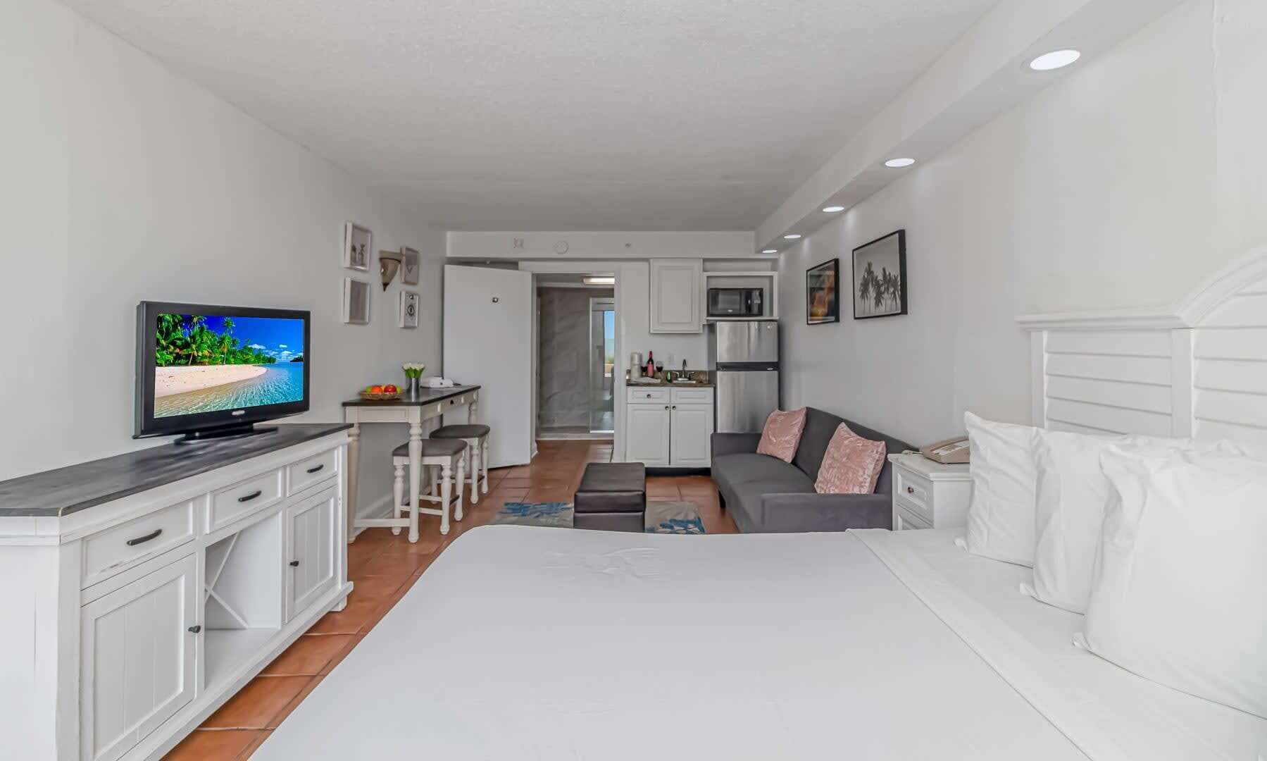 Un apartamento moderno con una cama grande, televisor, kitchenette y comedor.