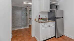 A compact kitchen with white cabinets, a stainless steel refrigerator, and a microwave. - Sea Mist 20102 Ocean Front Condo (Myrtle Beach)