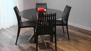 Een eetruimte met een ronde tafel, vier stoelen en een airconditioner aan de wand.