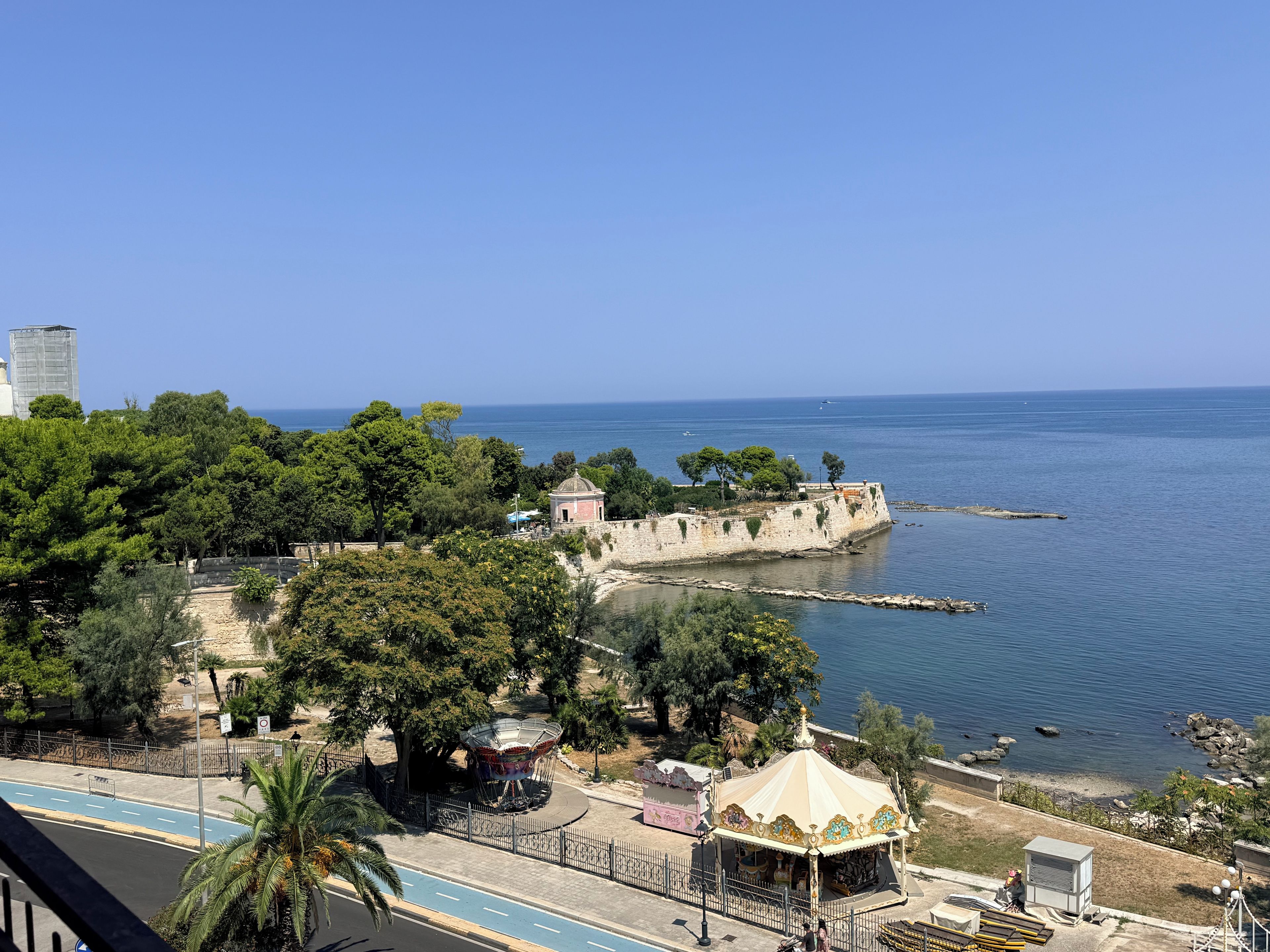 A coastal view with a historic fort, a carousel, and a clear blue sky.