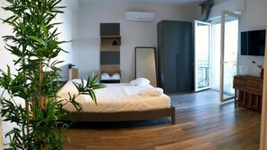 Een slaapkamer met een bed, een grote potplant, een kledingkast en een televisie.