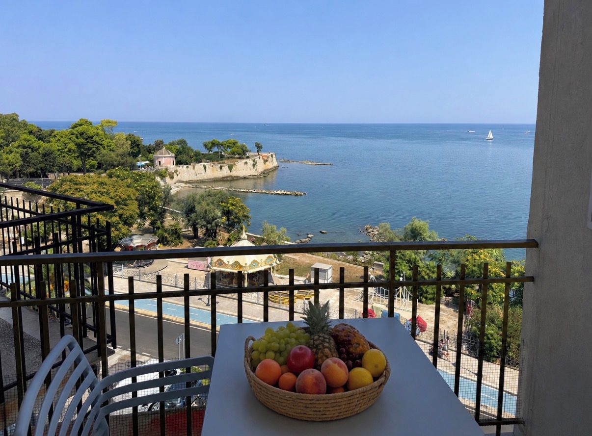 En balkon med frugtfad og havudsigt.