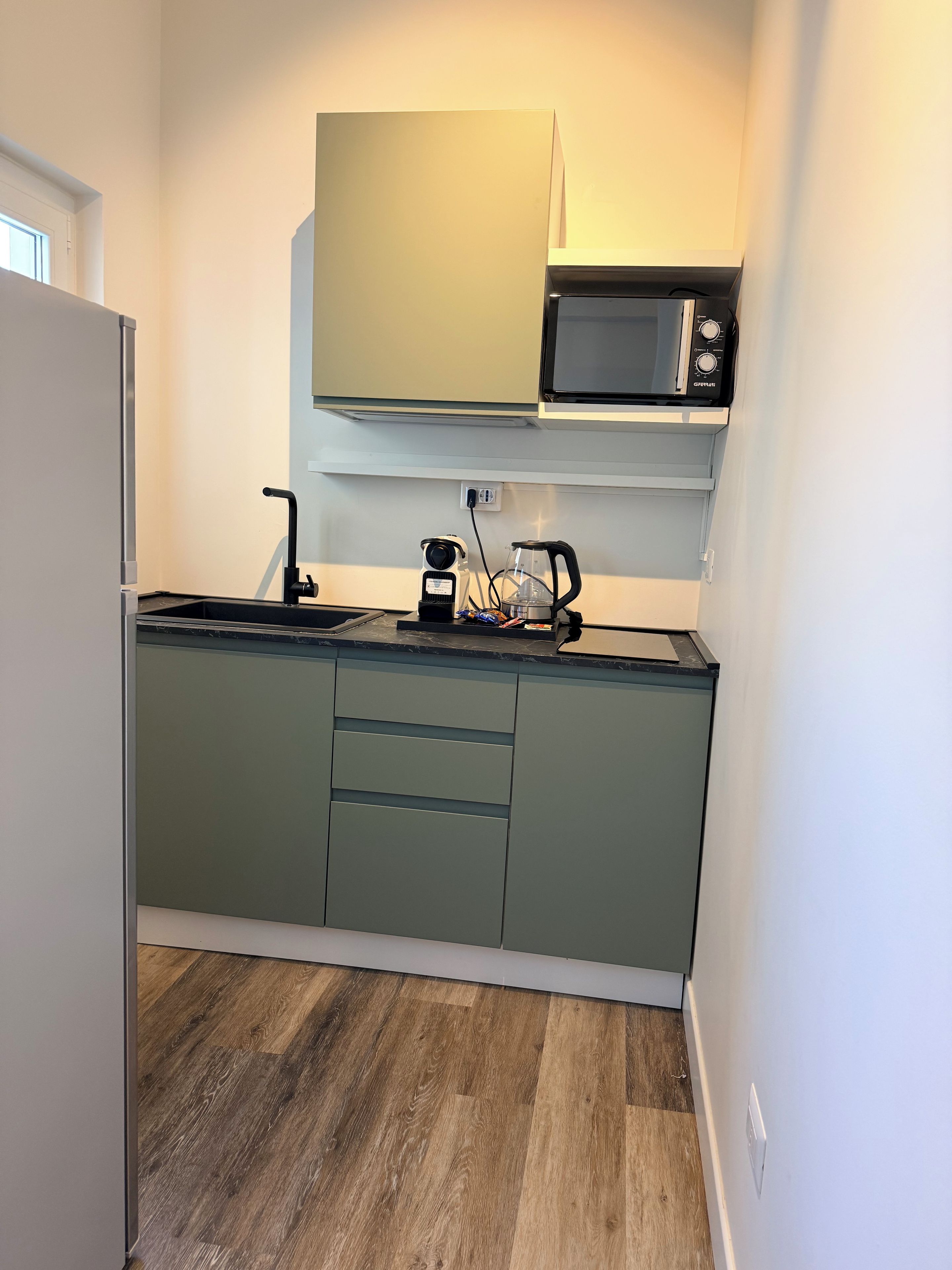 Una cocina compacta equipada con microondas, cafetera y lavabo.