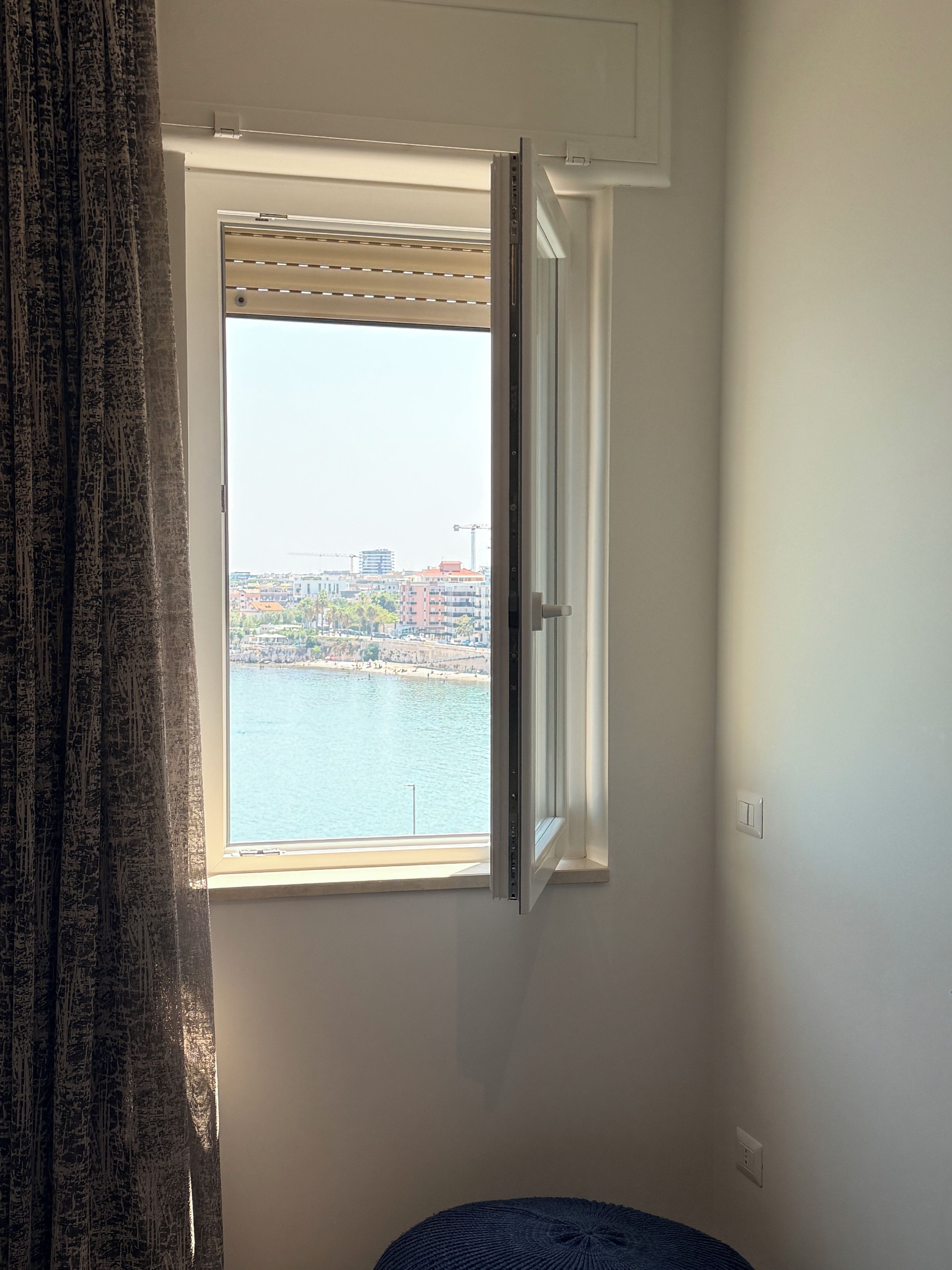 Una habitación con ventana que da a una masa de agua y un paisaje urbano.