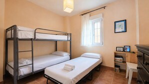 A dormitory room with bunk beds, a small desk, a dresser, and a window with curtains. - Los Cisnes, T2 Bajo - Ref.520B (Isla Canela)