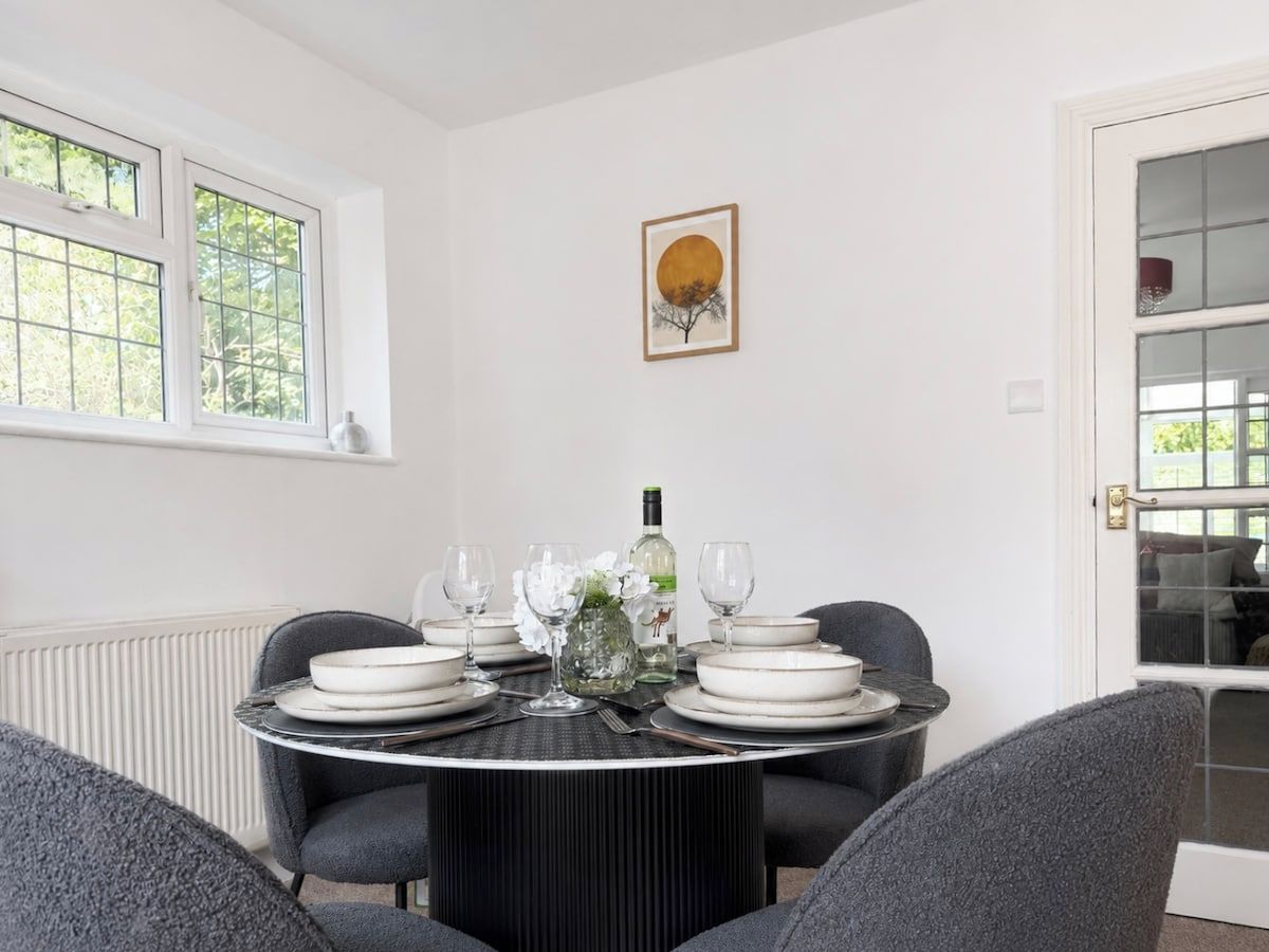 A dining area with a round table set for four, surrounded by grey chairs.