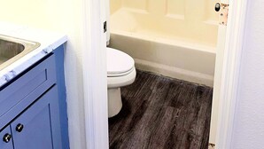 A bathroom with a toilet, a bathtub, and a shower area.
