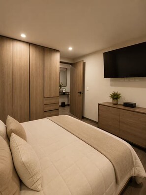 Ein Schlafzimmer mit einem Bett, einem Holzschrank, einem Flachbildfernseher und einer kleinen Pflanze auf einer Kommode.