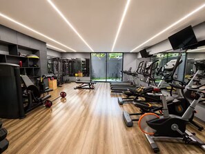Ein Fitnessstudio mit Laufbändern, Krafttrainingsgeräten und einer Spiegelwand.