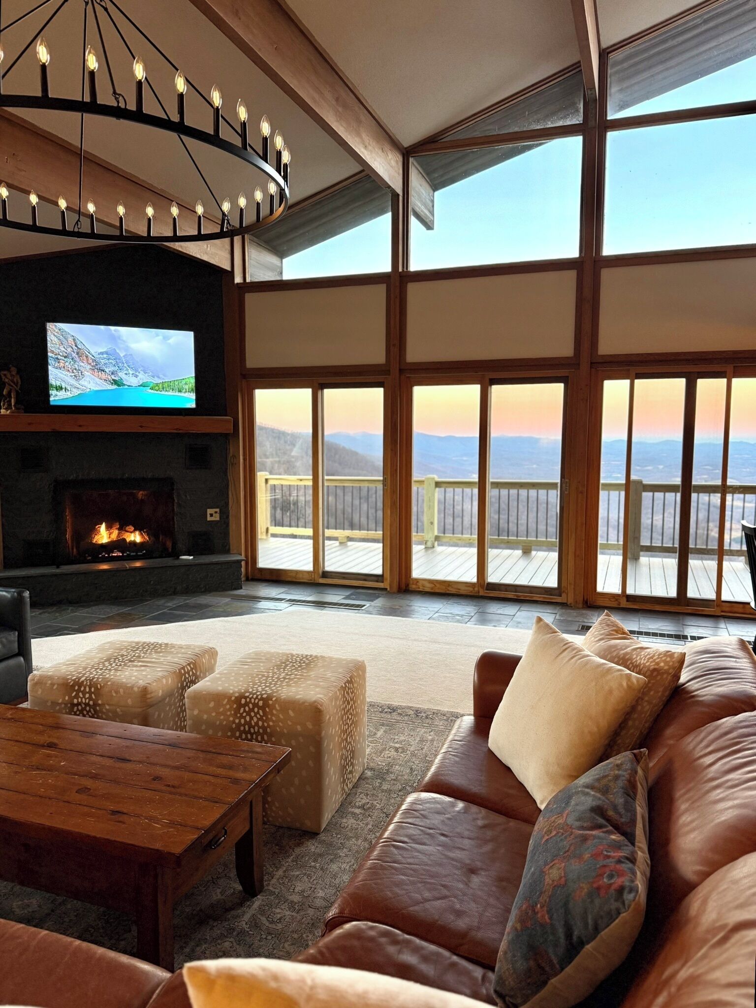A spacious living room with a fireplace, comfortable seating, and large windows offering a view of the outdoors.