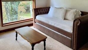 A room with a large window, a brown sofa, and a wooden table. - 6-bedroom mountain home with expansive views in Meadows of Dan, VA (Meadows of Dan)