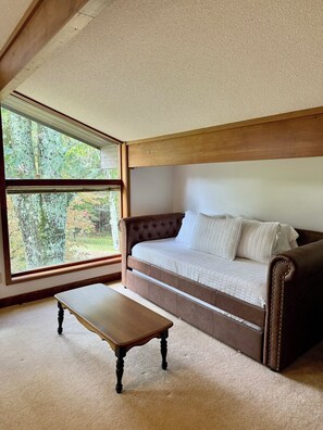 Ein Zimmer mit einem großen Fenster, einem braunen Sofa und einem Holztisch.