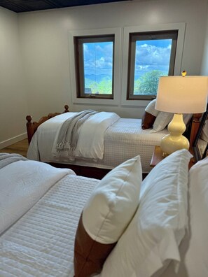 Ein Schlafzimmer mit zwei Betten, einem Fenster und einer Lampe.