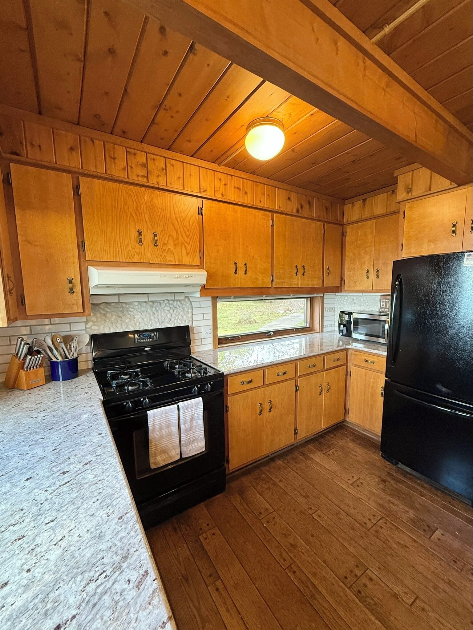 A kitchen with wooden cabinets, a black stove, and a refrigerator.