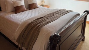 A bedroom with a wooden headboard, a bed with white bedding, a brown throw blanket, and a nightstand with a lamp. - 6-bedroom mountain home with expansive views in Meadows of Dan, VA (Meadows of Dan)