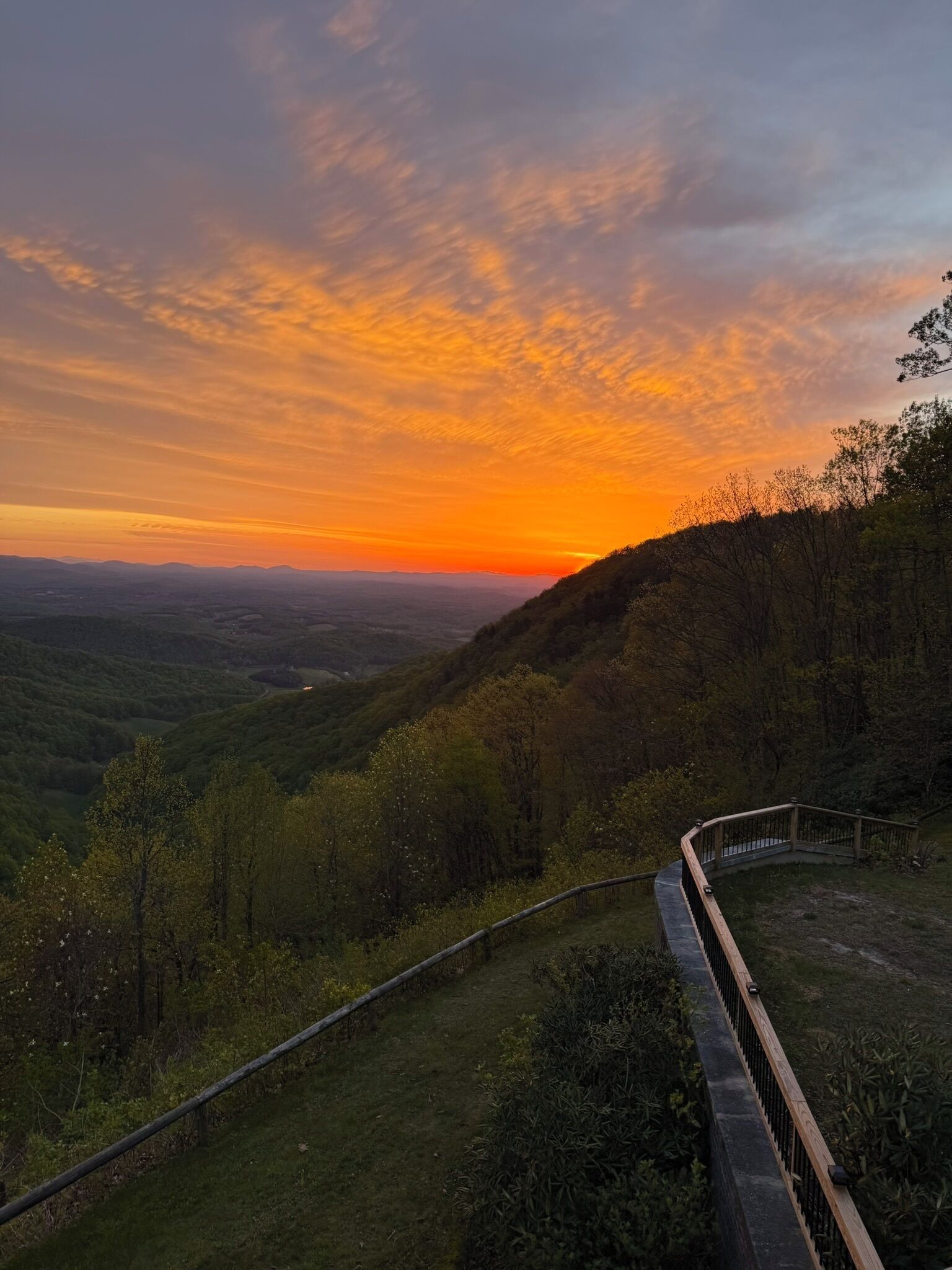 Uma paisagem pitoresca com colinas, uma ponte de madeira e um pôr do sol.