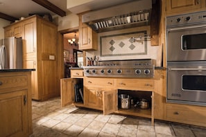 A kitchen with wooden cabinets, a built-in stove, and a stainless steel refrigerator.