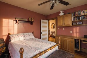 A bedroom with a bed, a ceiling fan, a bookshelf, and a door.