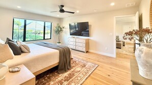 A bedroom with a bed, a TV, a plant, and a view of the outdoors. - The Ayres House North Gilham-UofO-Autzen-Oakway, Putting Green Large Turfed Yard (Eugene)