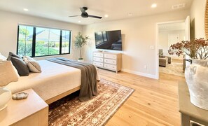 A bedroom with a bed, a TV, a plant, and a view of the outdoors. - The Ayres House North Gilham-UofO-Autzen-Oakway, Putting Green Large Turfed Yard (Eugene)