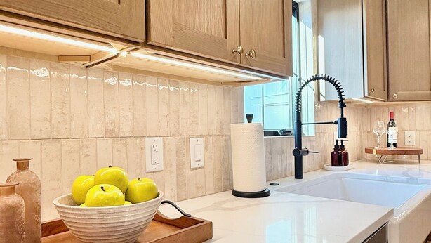A modern kitchen with wooden cabinets, a white countertop, and a bowl of apples. - The Ayres House North Gilham-UofO-Autzen-Oakway, Putting Green Large Turfed Yard (Eugene)