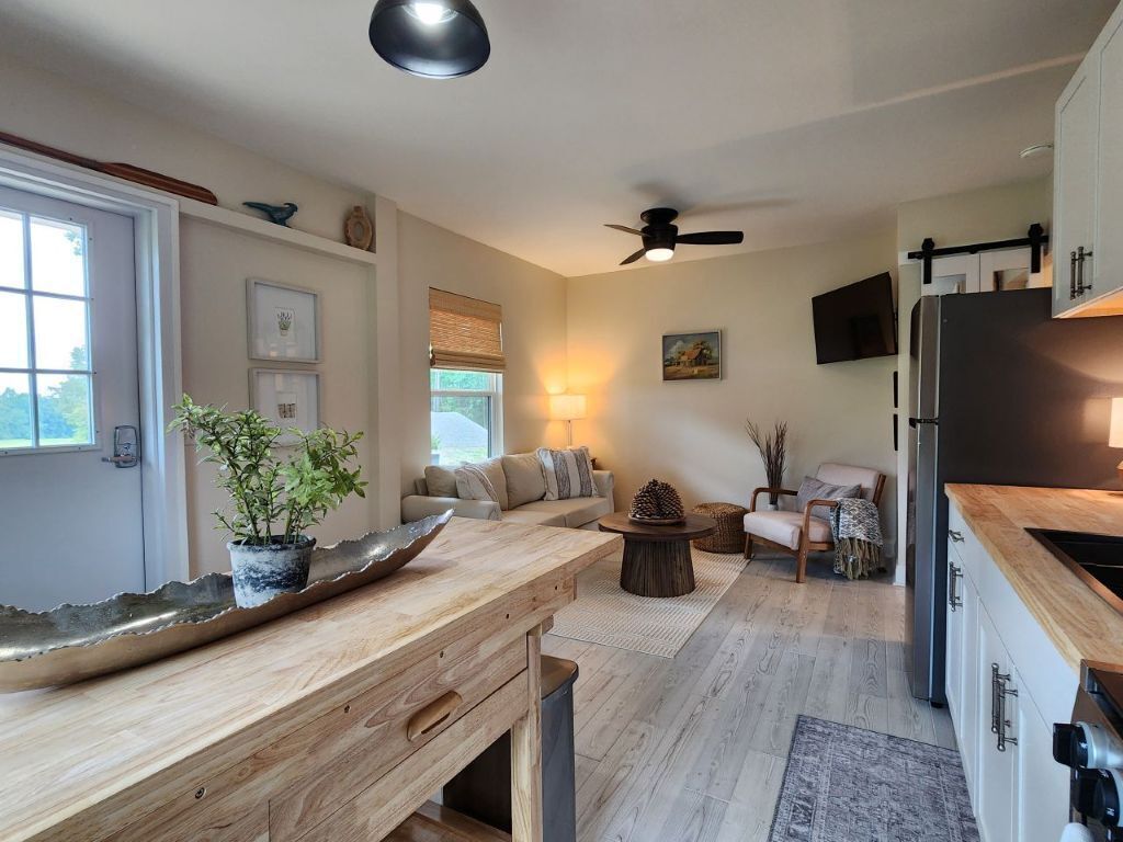 A modern kitchen with a wooden countertop, a dining area with a round table, and a seating arrangement with a sofa and chairs.