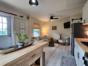 A modern kitchen with a wooden countertop, a dining area with a round table, and a seating arrangement with a sofa and chairs.