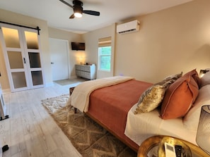 A bedroom with a bed, a nightstand, a dresser, a ceiling fan, and a window.