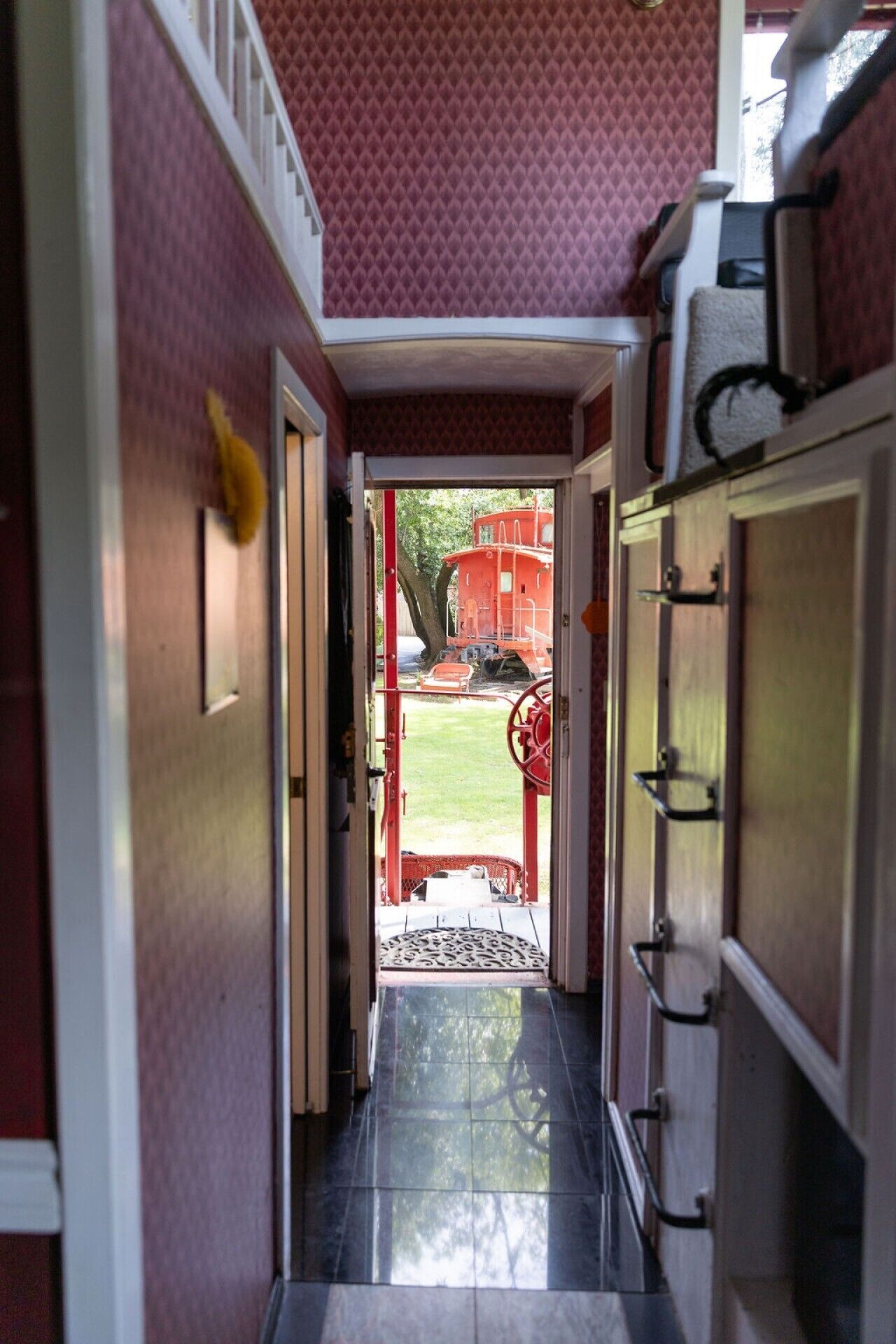 A narrow hallway with a tiled floor leading to an outdoor area.