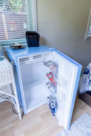 A compact refrigerator with a freezer compartment, containing several beverage cans.