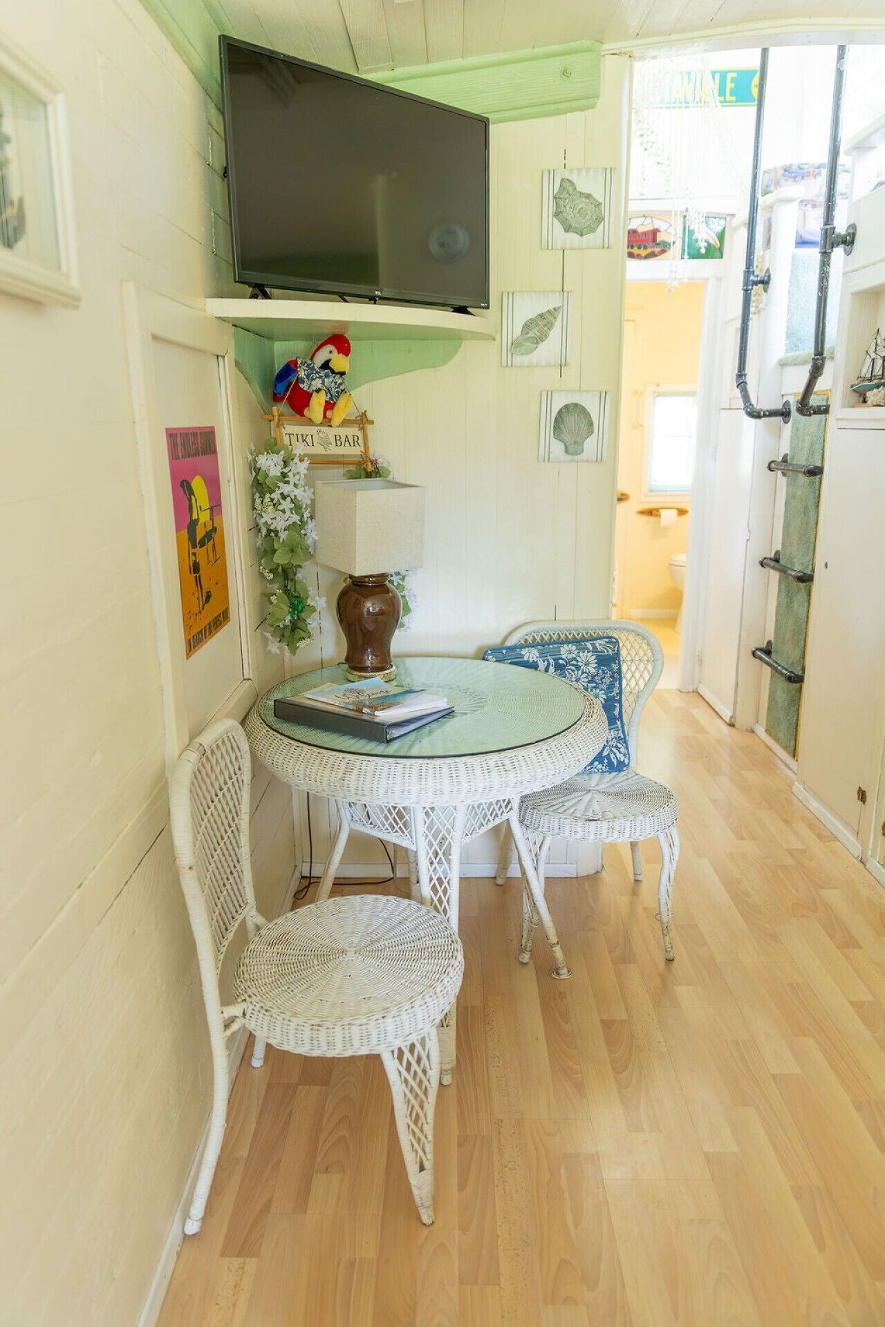 A dining area with a round table, two chairs, a television mounted above, and a sign indicating a bar.
