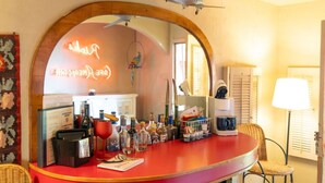 Een bar met een gebogen toonbank, een neonreclame en diverse flessen en glazen.