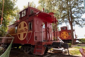 En röd vagn från Santa Fe-tåget, med en stege och en plattform, placerad på ett spår med träd i bakgrunden.