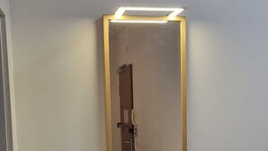 En gang med et spejl på væggen, en lampe over det, og en dør i enden.