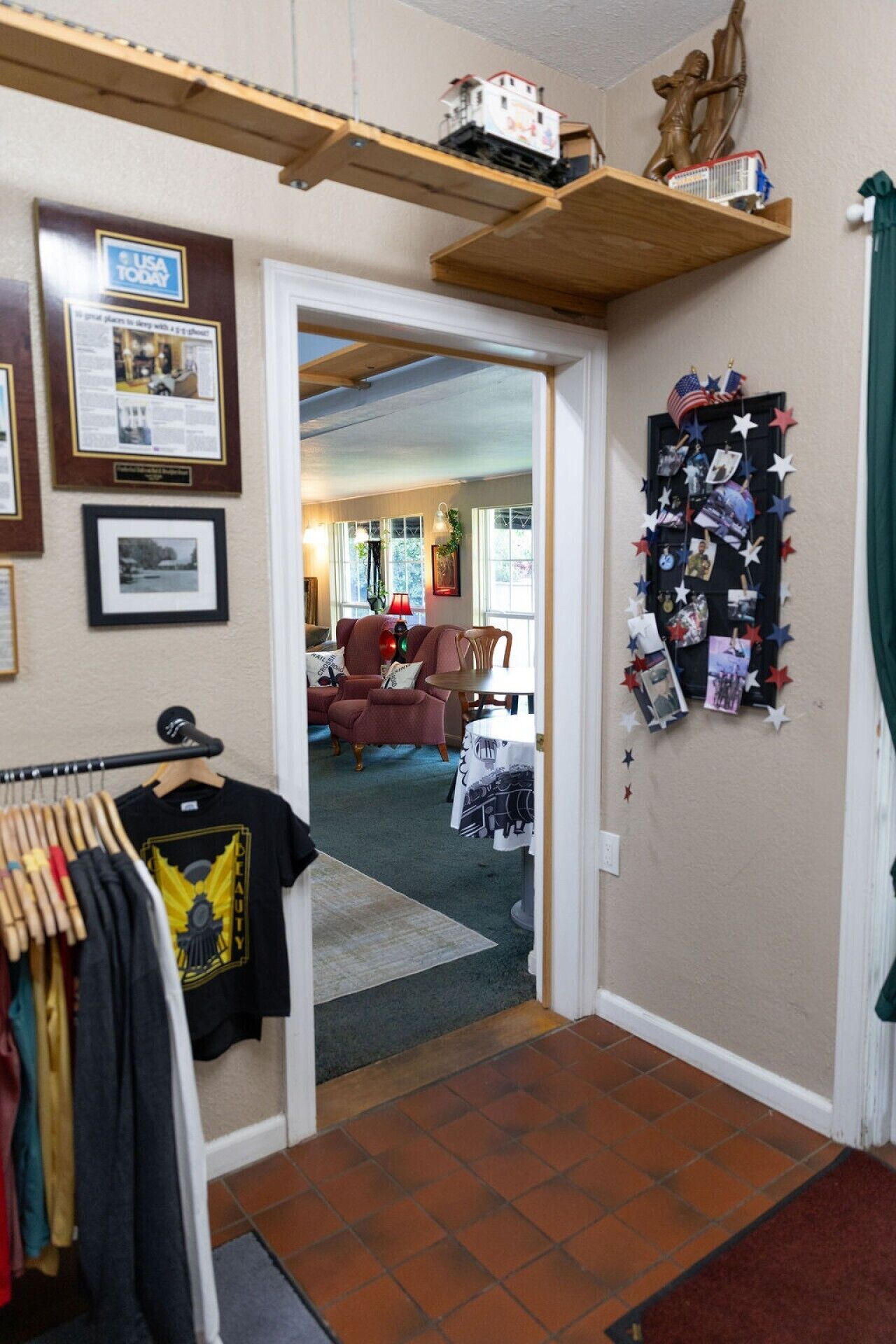 A hallway leading to a living room with a sofa, a table, and a wall decorated with photos and memorabilia.